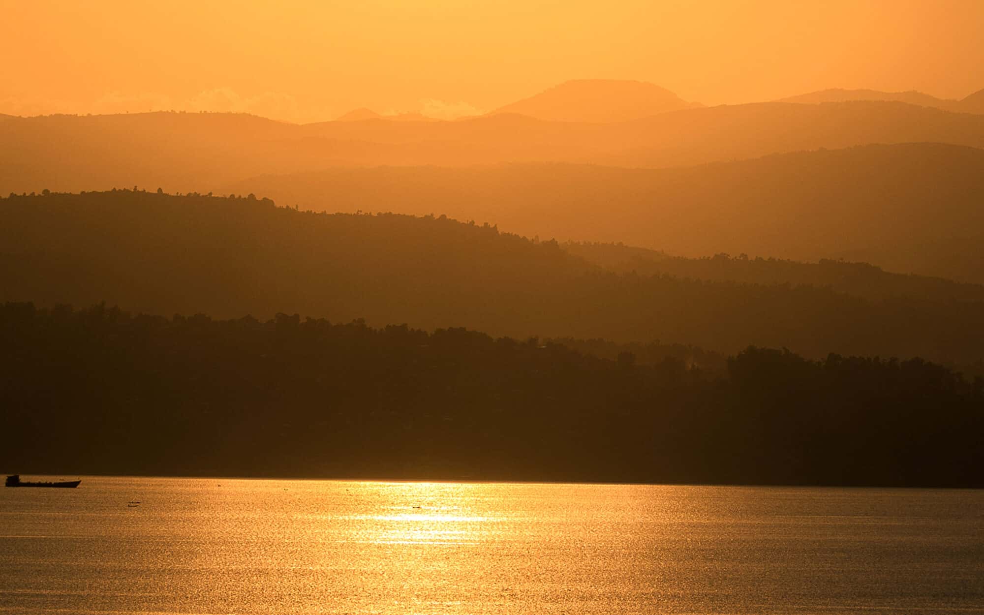 Golden sunset over serene lake and distant mountains.